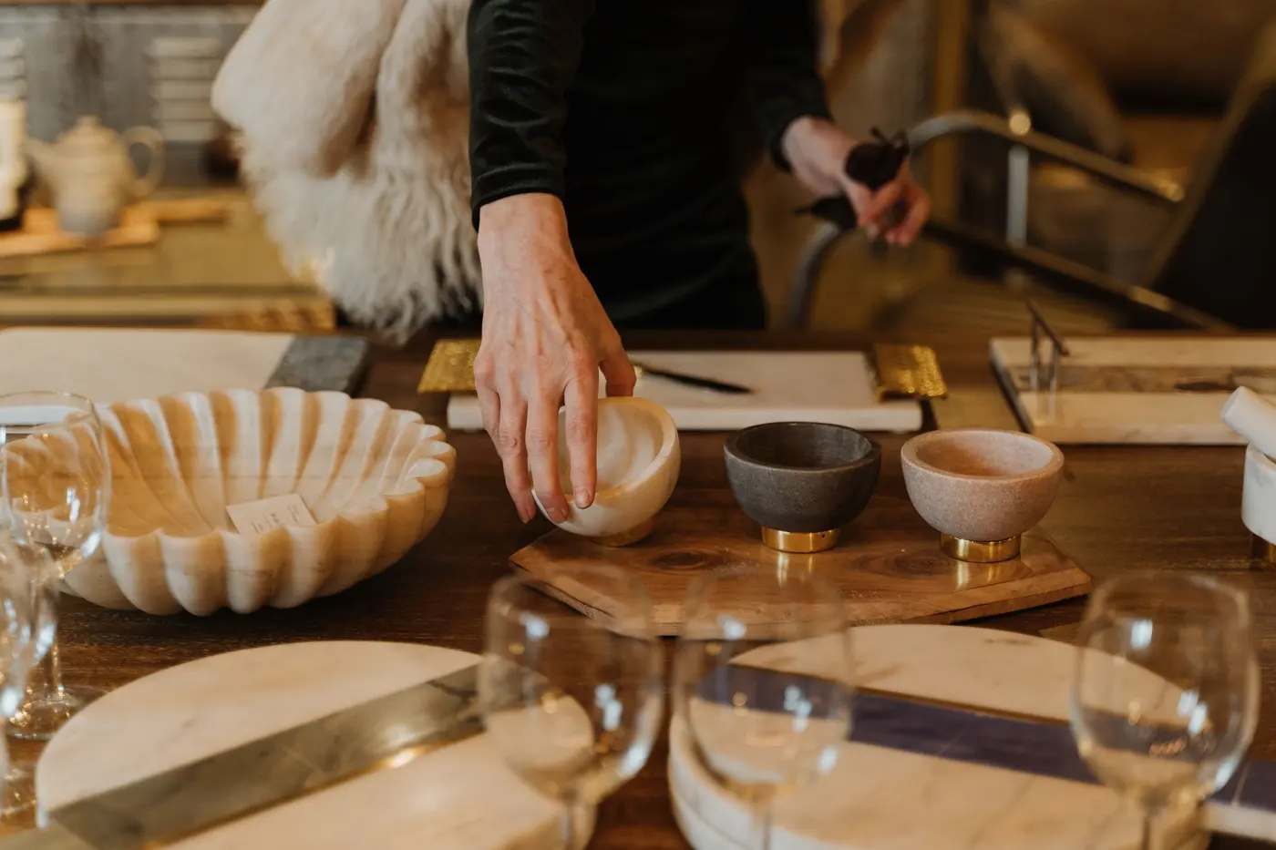 Hands arranging hand-made ceramic pieces on a wooden table
