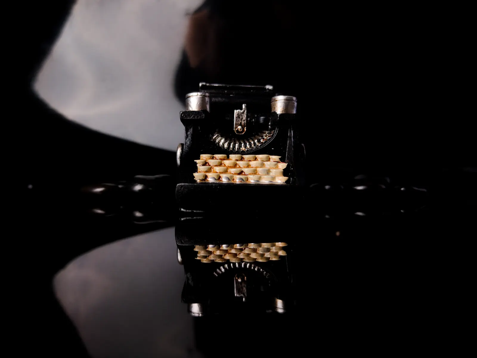 An antique typewriter on a dark reflective surface